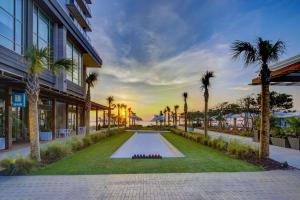 um pátio com piscina em frente a um edifício com palmeiras em Marriott Virginia Beach Oceanfront Resort em Virginia Beach