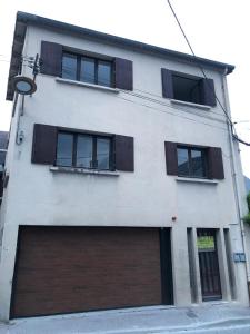 un edificio blanco con dos puertas y ventanas de garaje en Appartement Familial, en Marignac