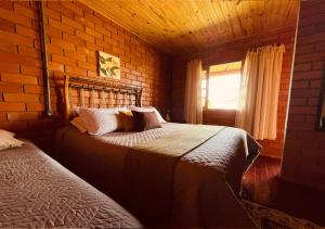 a bedroom with two beds and a brick wall at Fazenda Santa Rita Turismo Rural in Bom Jardim da Serra