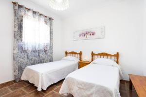 two beds in a white room with a window at El Retamar, naturaleza y paisajes in Santiago del Teide