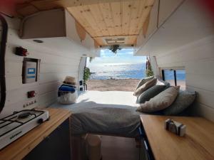 a caravan with a bed and a view of the beach at Sleepfurgo in Las Palmas de Gran Canaria