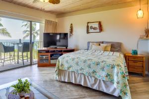 a bedroom with a bed and a flat screen tv at Sunny Waianae Condo with Ocean View! in Waianae
