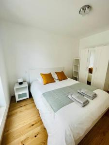 a white bedroom with a large white bed with orange pillows at Brand New 3 bedrooms with Terrace and Parking - 142-92 in Luxembourg