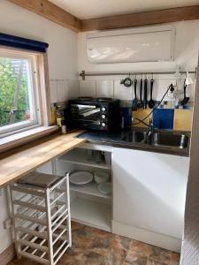 una pequeña cocina con fregadero y microondas en Fint sjönära annex en Växjö