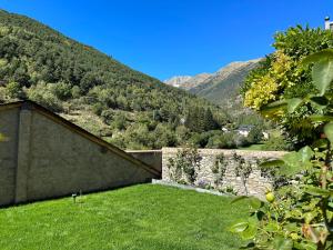 a garden with a wall and mountains in the background at Apartament Casa Sastre in Espot