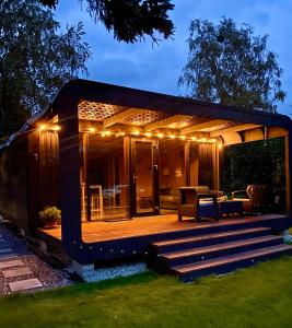 ein Haus mit einer Terrasse mit Beleuchtung in der Unterkunft A tiny house with a garden and a hot tube in Pringi