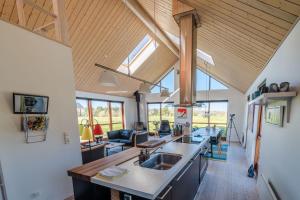 a kitchen and living room with wooden ceilings and windows at Vidunderlig fritidshus ved Skov og Golfbane in Skjern