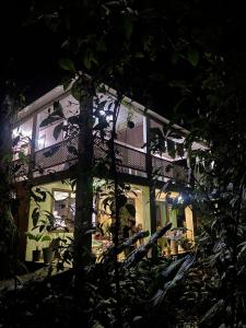 une maison la nuit avec des personnes assises devant elle dans l'établissement Casa Jaguar Tortuguero, à Tortuguero