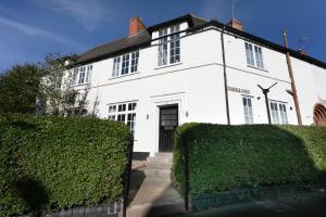 a white house with a hedge in front of it at Large 4 bed house Leicester in Leicester