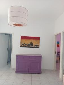 a purple cabinet in a room with a painting on the wall at VIOLA in Vila do Porto