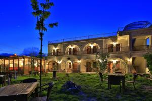 a building with tables and chairs in a yard at night at Kemal's Guest House in Göreme