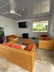 sala de estar con muebles de mimbre y TV de pantalla plana. en Casa en Condominio Carmen de Apicala en Carmen de Apicalá