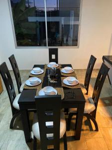 una mesa de comedor negra con sillas y platos. en Casa en Condominio Carmen de Apicala, en Carmen de Apicalá