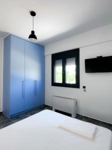 a bedroom with a white bed and a blue cabinet at Alexandra's Place in Galatás