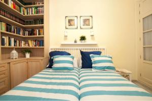 Schlafzimmer mit einem Bett mit blau-weißen gestreiften Kissen in der Unterkunft Magic Point Las Setas in Sevilla