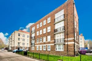 a red brick building with windows on a street at Beautiful 2bedroom close to Brick Lane in London