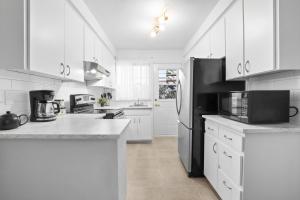 eine Küche mit weißen Schränken und einem schwarzen Kühlschrank in der Unterkunft Free Parking Gorgeous 3Bedrooms in Montreal
