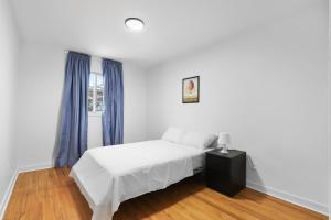 ein weißes Schlafzimmer mit einem Bett und einem Fenster in der Unterkunft Free Parking Gorgeous 3Bedrooms in Montreal