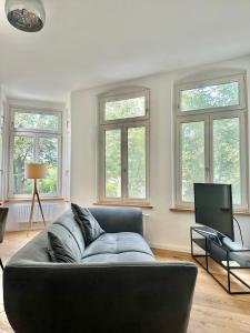 a living room with a couch and a tv at Modernes City-Apartment mit Blick in den Park und 2 Bäder H9 in Oldenburg