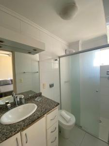 La salle de bains est pourvue d'un lavabo, de toilettes et d'un miroir. dans l'établissement Apartamento com sacada e churrasqueira, à Balneário Camboriú