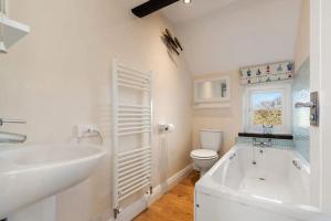a bathroom with a tub and a toilet and a sink at Meadowsweet Cottage Jacuzzi Edition in Saundersfoot