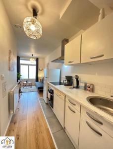 a kitchen with white cabinets and a wooden floor at Luna Night Seh’Loué in Saint-Brieuc