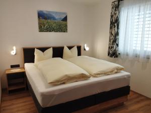a bedroom with a bed with white pillows and a window at Appartement Lisi`s Dahoam in Achenkirch
