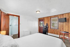 a bedroom with a white bed and a television at Eagles Nest Motel Unit 2 in Escanaba