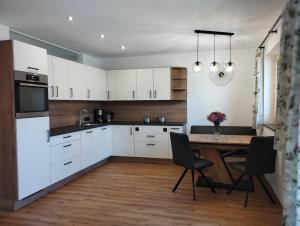 a kitchen with white cabinets and a table and chairs at Appartement Lisi`s Dahoam in Achenkirch