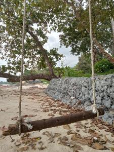 a stone wall and trees on a sandy beach at The BoatBnB in Kampong Pandan
