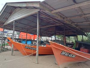 three boats sitting under a roof on the beach at The BoatBnB in Kampong Pandan