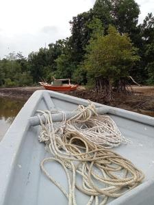a boat with a pile of rope on the water at The BoatBnB in Kampong Pandan