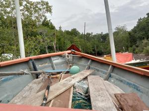 a boat with a wooden seat and a paddle at The BoatBnB in Kampong Pandan