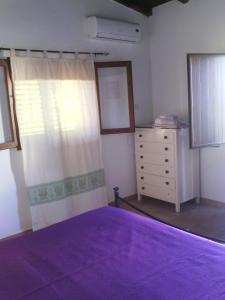 a bedroom with a purple bed and a dresser at Agriturismo Silitta in Siniscola