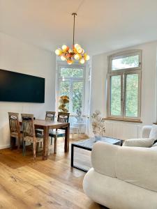 ein Wohnzimmer mit einem Tisch und einem TV in der Unterkunft Modernes City-Apartment mit Blick in den Park und 2 Bäder H9 in Oldenburg