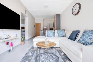 a living room with a white couch and a clock on the wall at Grandeur by Mall of Africa in Midrand