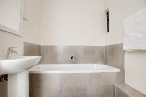 a bathroom with a white tub and a sink at Grandeur by Mall of Africa in Midrand +22 photos
