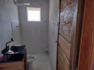 a bathroom with a toilet and a window and a door at Chale 8A in Cunha
