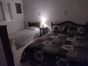 a bedroom with two beds and a table with a lamp at Chale 8A in Cunha