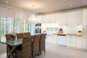 a kitchen with white cabinets and a table and chairs at Luxurious Villa Kinos with Jacuzzi in Rovaniemi
