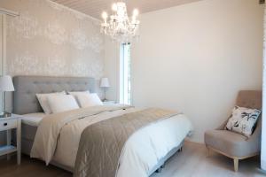 a bedroom with a bed and a chandelier and a chair at Luxurious Villa Kinos with Jacuzzi in Rovaniemi