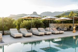 - une piscine bordée de chaises longues et de parasols dans l'établissement Beach Villas in Crete - Alope & Ava member of Pelagaios Villas, à Ierápetra