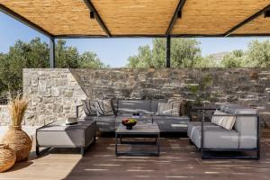 a patio with couches and a stone wall at Beach Villas in Crete - Alope & Ava member of Pelagaios Villas in Ierapetra