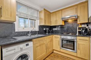 een keuken met houten kasten en een wasmachine bij Apartment in Shoreditch/ Old St in Londen +15 foto's