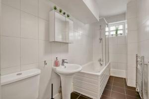 a white bathroom with a sink and a bath tub at Apartment in Shoreditch/ Old St in London