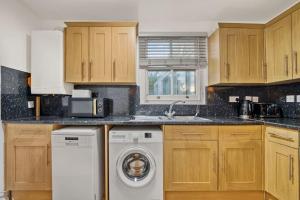 a kitchen with wooden cabinets and a washer and dryer at Apartment in Shoreditch/ Old St in London