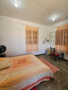 1 dormitorio con 1 cama y 1 silla en Chalé Arcos do Sol - Carrancas, en Carrancas