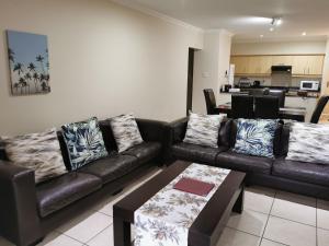 a living room with a leather couch and a table at Tortuga 22 - Caribbean Estates in Port Edward