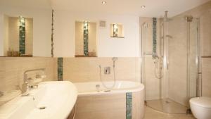 a bathroom with a tub and a shower and a sink at Biloba Garden in Wengern +16 photos