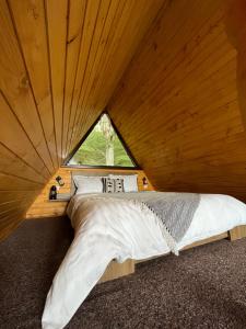 Łóżko w drewnianym pokoju z oknem w obiekcie Căsuțele de sub pădure w mieście Avrig